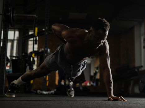 African american man doing one arm push ups in the gym