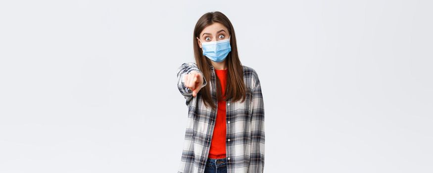 Coronavirus outbreak, leisure on quarantine, social distancing and emotions concept. Astonished and impressed, excited girl recognize someone, pointing finger camera, wear medical mask.