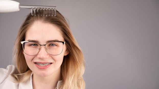 Caucasian woman combing her hair with a darsonval device