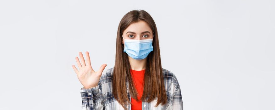 Coronavirus outbreak, leisure on quarantine, social distancing and emotions concept. Attractive female in medical mask and casual clothes show five fingers, number of order, white background.