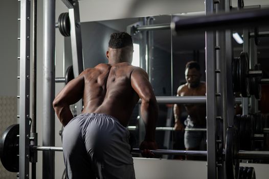 Handsome afro american man posing showing back muscles in gym