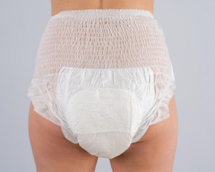 Rear view of a Woman in adult diapers on a white background. Incontinence problem