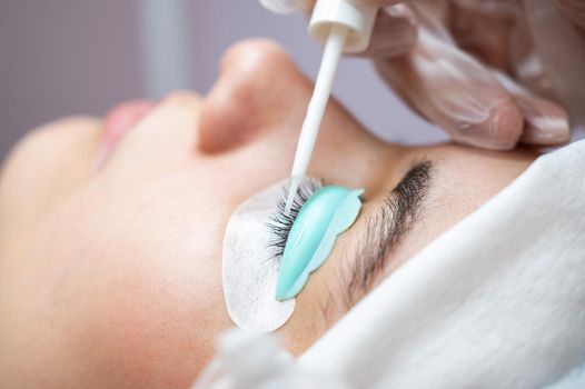 Young woman undergoing eyelash tinting and lamination procedure