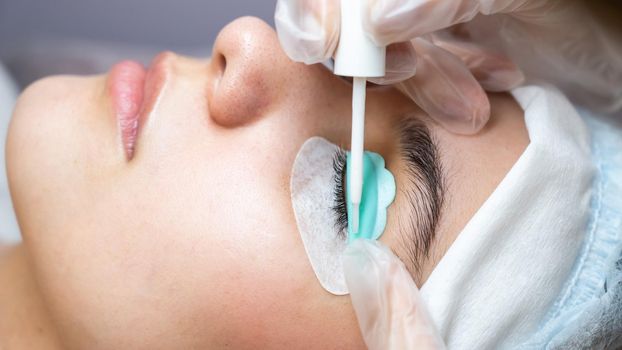 Young woman undergoing eyelash tinting and lamination procedure