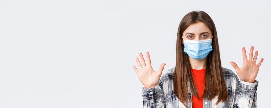 Coronavirus outbreak, leisure on quarantine, social distancing and emotions concept. Attractive caucasian woman in medical mask show ten fingers, amount or quantity, white background.