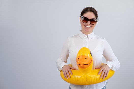 Caucasian woman in a white shirt dreaming of a vacation and wearing sunglasses and an inflatable duck