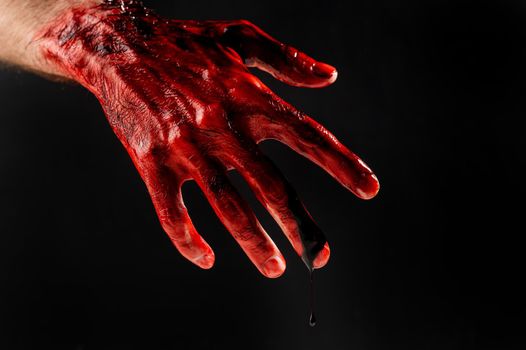 Close-up of a male hand stained with blood on a black background