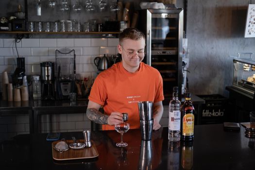 Barman is making cocktail at night club. stylish young man mixing a cocktail in a dark loft cafe. alcohol drink in modern bar. male bartender.