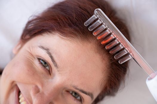 Caucasian woman on a hair care procedure using the Darsonval apparatus