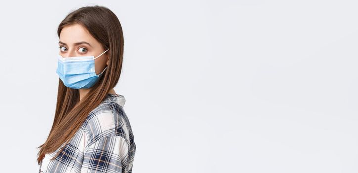 Coronavirus outbreak, leisure on quarantine, social distancing and emotions concept. Profile shot of serious young attractive woman, student in medical mask turn face camera.