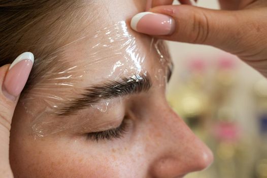 The master uses a plastic film during lamination of the eyebrows