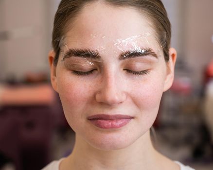 Caucasian woman on the procedure of permanent styling and coloring of eyebrows