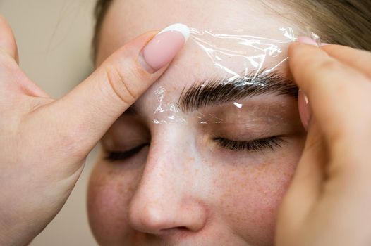 The master uses a plastic film during lamination of the eyebrows