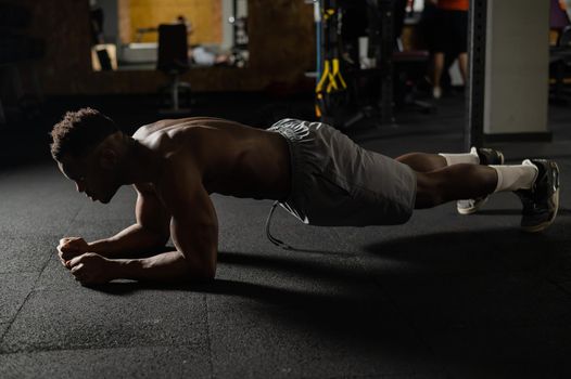 Shirtless african american man doing an elbow plank in the gym