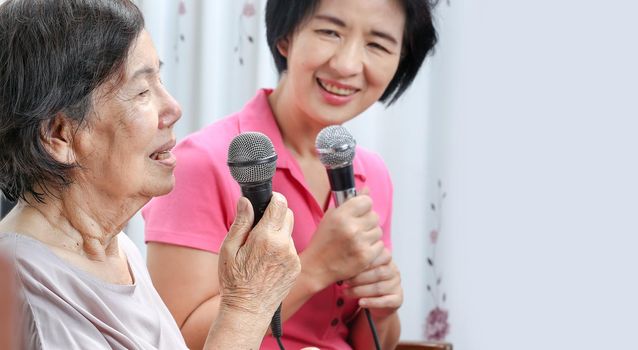 Elderly woman sing a song with daughter at home.