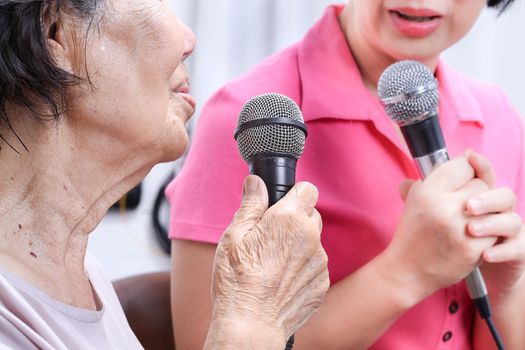 Elderly woman sing a song with daughter at home.