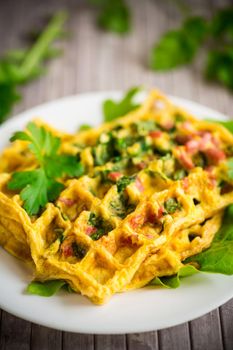 Egg omelet stuffed with greens and sausage fried in the form of waffles, on a wooden table