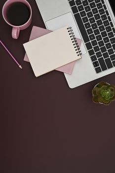 Flat lay computer laptop, notepad and coffee cup on purple background.