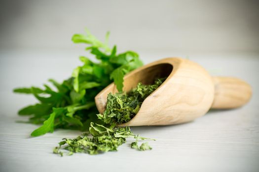 dried green organic arugula, seasoning, on a light wooden background