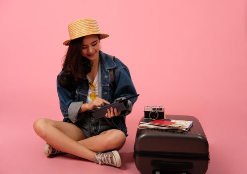 young asian woman backpacker traveler holding tablet. journey trip travel. studio shot