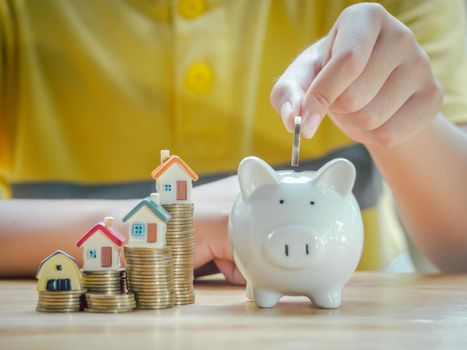Asian boy holding coins drop a container saving money to save money invest for future and buy home.Concept loan, property ladder, financial, real estate investment and bonus.