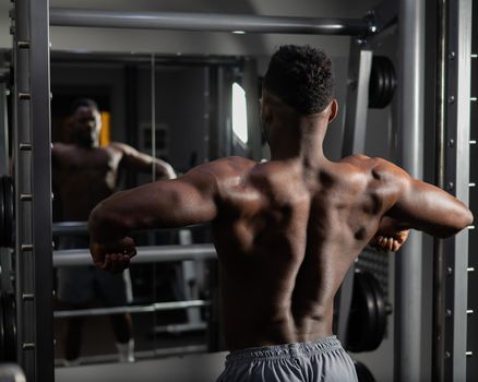 Handsome afro american man posing showing back muscles in gym