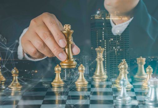 Hand of businessman holding gold king chess on stock market or forex trading graph chart with cityscape image economy trend for digital financial investment.Management or leadership strategy concept.