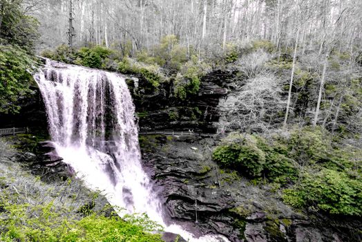 A scenic waterfall roadside going over the cliff down to the boulders and rocks below where you can no longer drive under but can walk underneath the raging waters