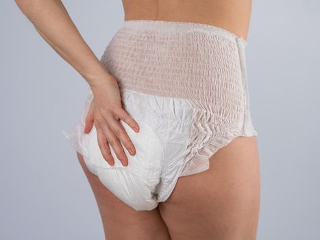 Rear view of a Woman in adult diapers on a white background. Incontinence problem