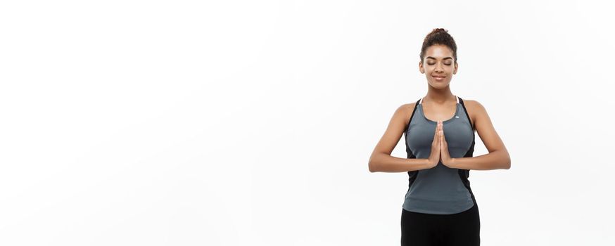 Healthy and Fitness concept - Beautiful American African lady in fitness clothing doing yoga and meditation. Isolated on white background