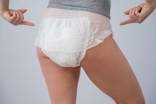 Rear view of a woman pointing at adult diapers. Incontinence problem