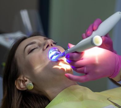 The process of removing braces.Beautiful woman in dental chair during procedure of installing braces to upper and lower teeth. Dentist and assistant working together, dental tools in their hands.