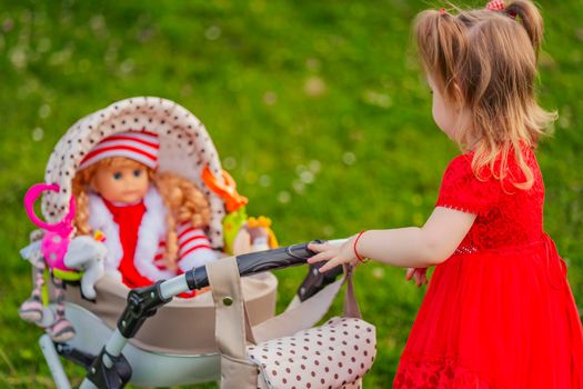 girl plays with her doll who is sitting in a toy stroller