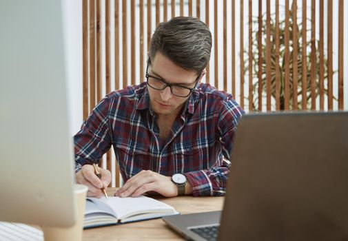 Cheerful businessman taking notes while working in the office.