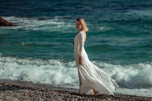 Middle aged woman looks good with blond hair, boho style in white long dress on the beach decorations on her neck and arms