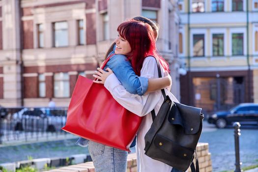 Meeting of two teenage girls friends, outdoor on city street. Happy joyful fashionable females embrace greeting. Joy happiness together, friendship communication lifestyle, youth concept