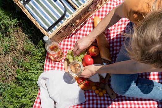 Young woman in park outside at sunny day, enjoying summertime dreaming and drinking wine. Millennial woman having picnic outdoors in sunny day