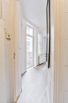 Room with door to balcony and narrow long corridor in perspective in modern house with ceiling beams