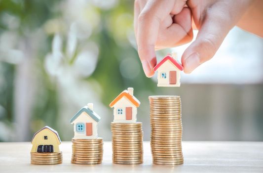 Hand of boy holding home or house on gold coins stack to saving money invest for future and buy home.Concept loan, property ladder, financial, real estate investment and bonus.