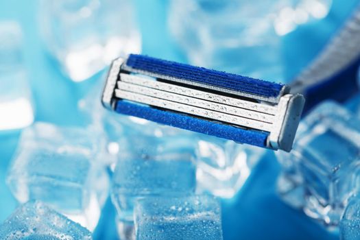 Shaving machine on a blue background with ice cubes. The concept of cleanliness and frosty freshness