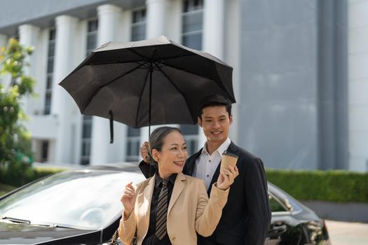 Happy senior old asian businesswoman discussion talking about new project with young asian male colleague at car park