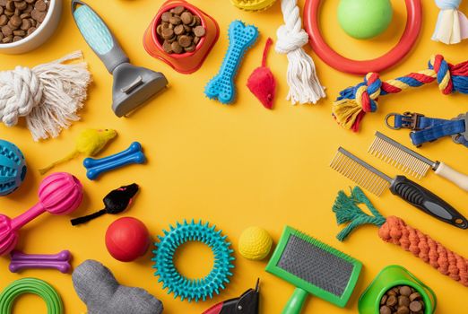 Pet care concept, various pet accessories and tools, toys, balls, brushes on yellow background, flat lay pattern