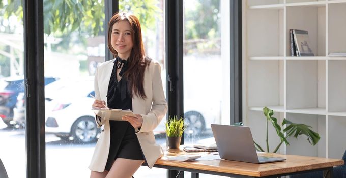 Charming Asian woman working at the office using a laptop Looking at the camera..