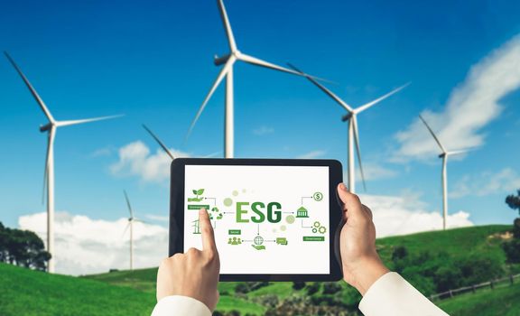 Green business transformation for environment saving and ESG business concept. Businessman using tablet to set corporate goal toward environmental friendly management and alternative clean energy use.