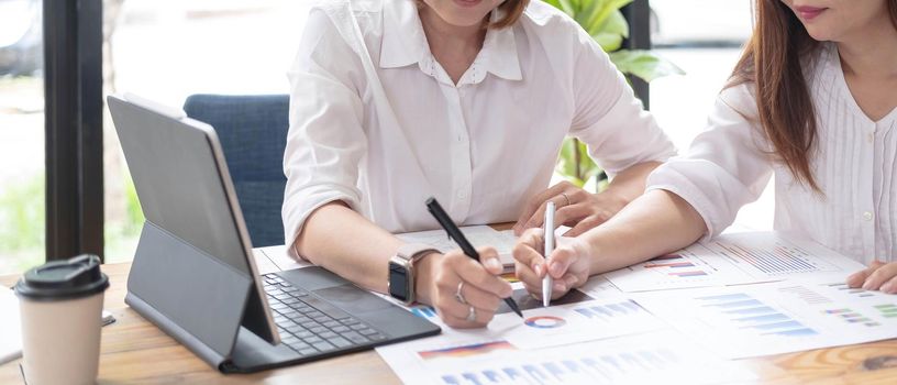 Two women analyzing documents while sitting on a table in office. Woman executives at work in office discussing some paperwork..