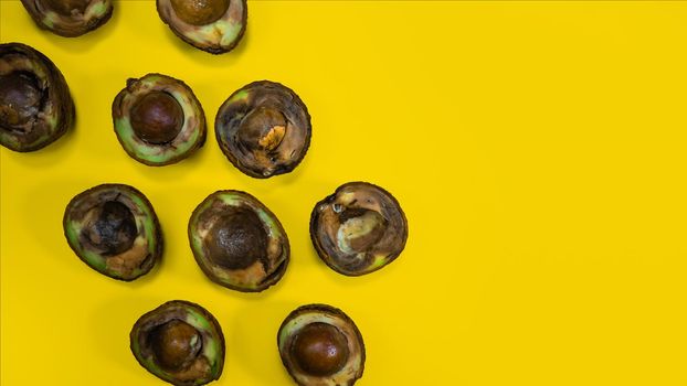 Bad many Avocado on Yellow Background. Food Fruits cannot be eaten. Overripe avocado fruit cuts in halfs. Stop wasting food. Unhelthy bad food Concept. Copy Space.