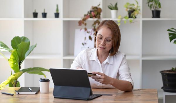 Asian senior woman using a laptop with a credit card..