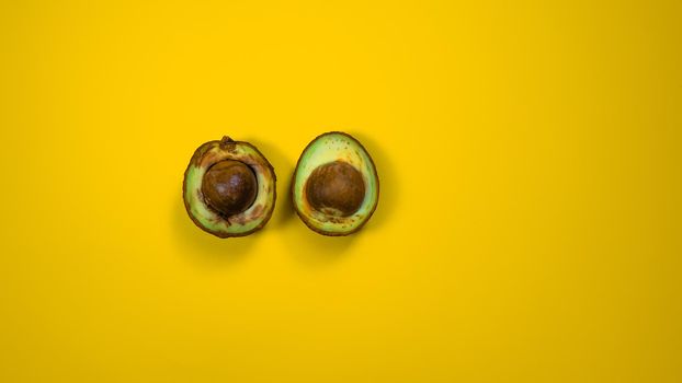 Two Half Bad Avocado.The seed avocado and the inside is visible. Rotten Avocado on yellow background Copy space.