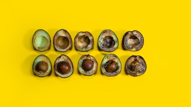 Avocado evolution from good to rotten fruits. Creative composition many avocado cuts in halfs on yellow background. Rotten avocado piles cannot be eaten.