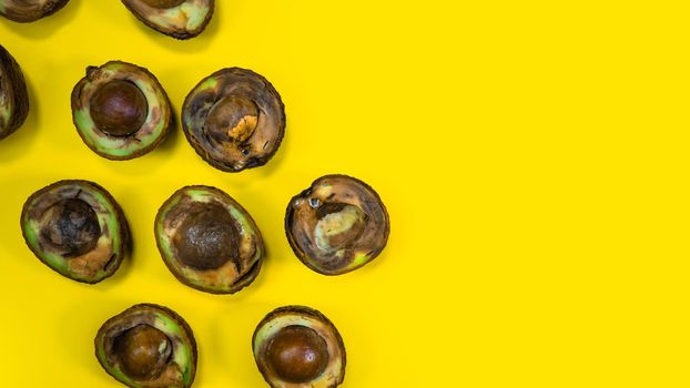 Rotten Avocado halves on Yellow Background. Food Fruits cannot be eaten. Overripe avocado fruit cuts in halfs. Stop wasting food. Unhelthy bad food Concept. Copy Space.